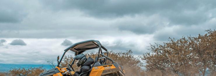 Quad kaufen: Orange CFMOTO Side-by-Side (UTV) driftet im Gelände auf Schotter, Fahrer mit Helm, Staubwolke bei Halle (Saale).